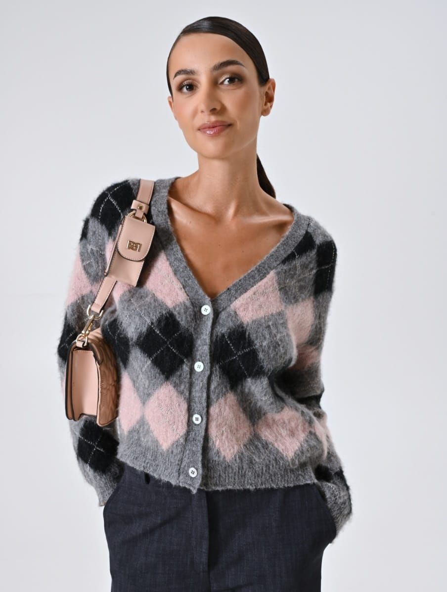 Wollen vest met roze-zwart ruitpatroon, gedragen met een roze schoudertas.