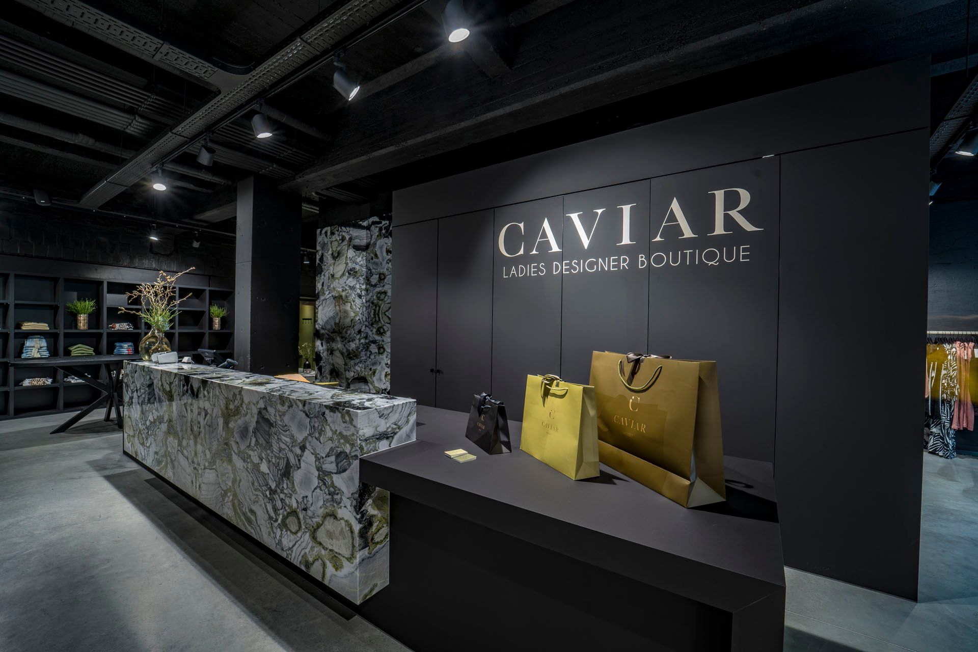 Marmeren toonbank met gele tassen voor de muur met het opschrift CAVIAR Ladies Designer Boutique.